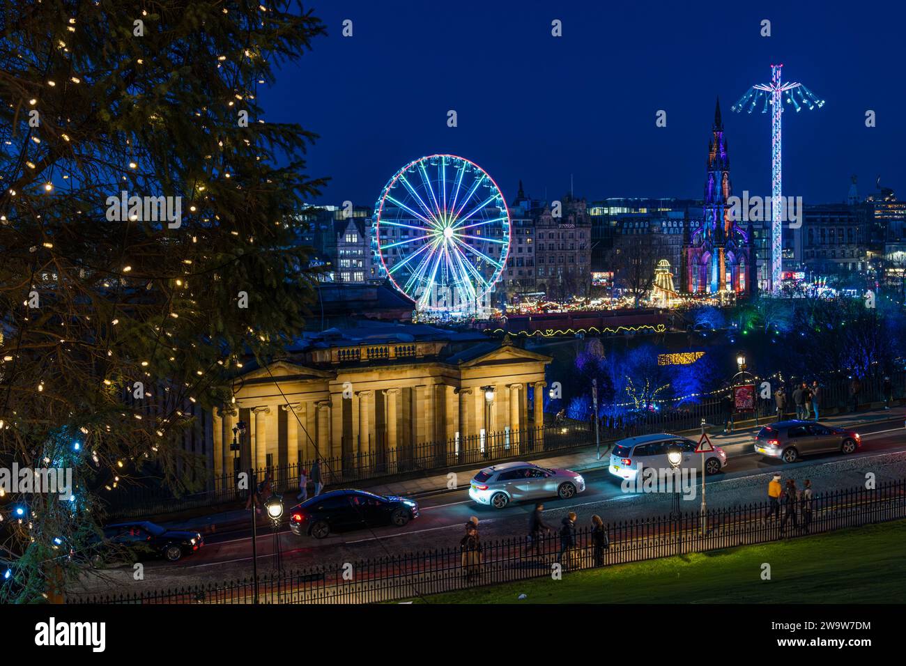 Big ferris wheel and star flyer fairground rides lit up at night at