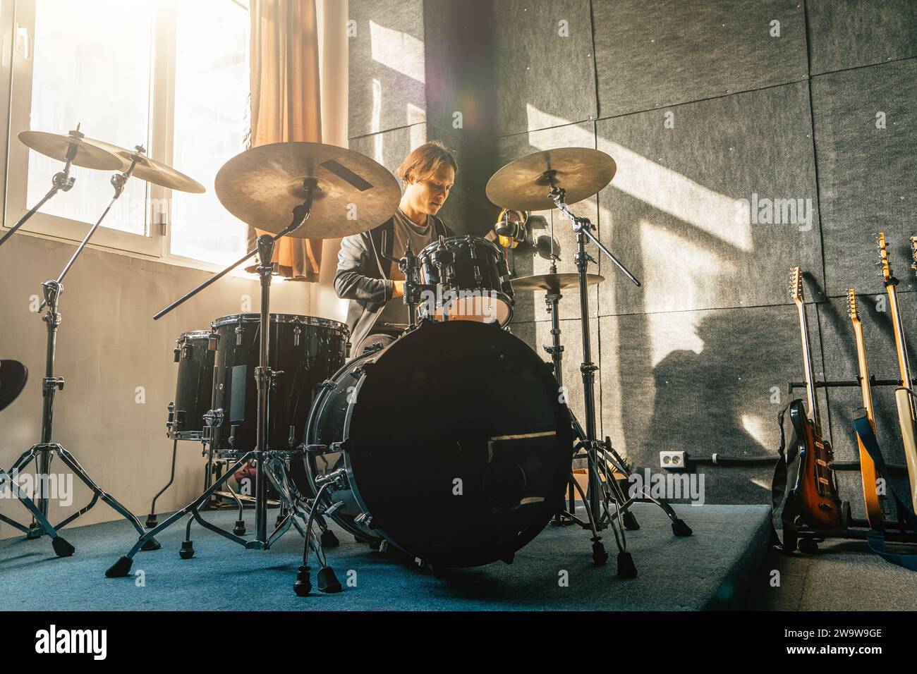 Portrait of drummer sitting at drum kit in sound recording studio at music band rehearsal. Stock Photo