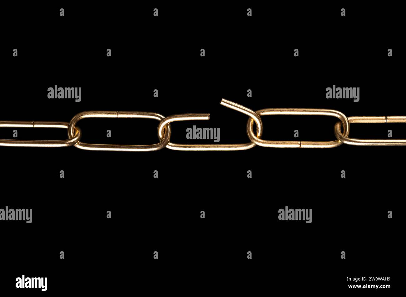 Steel chain with shiny brass plated surface, and with one link bent open, over black. Straight shaped smooth, decorative ring chain. Stock Photo