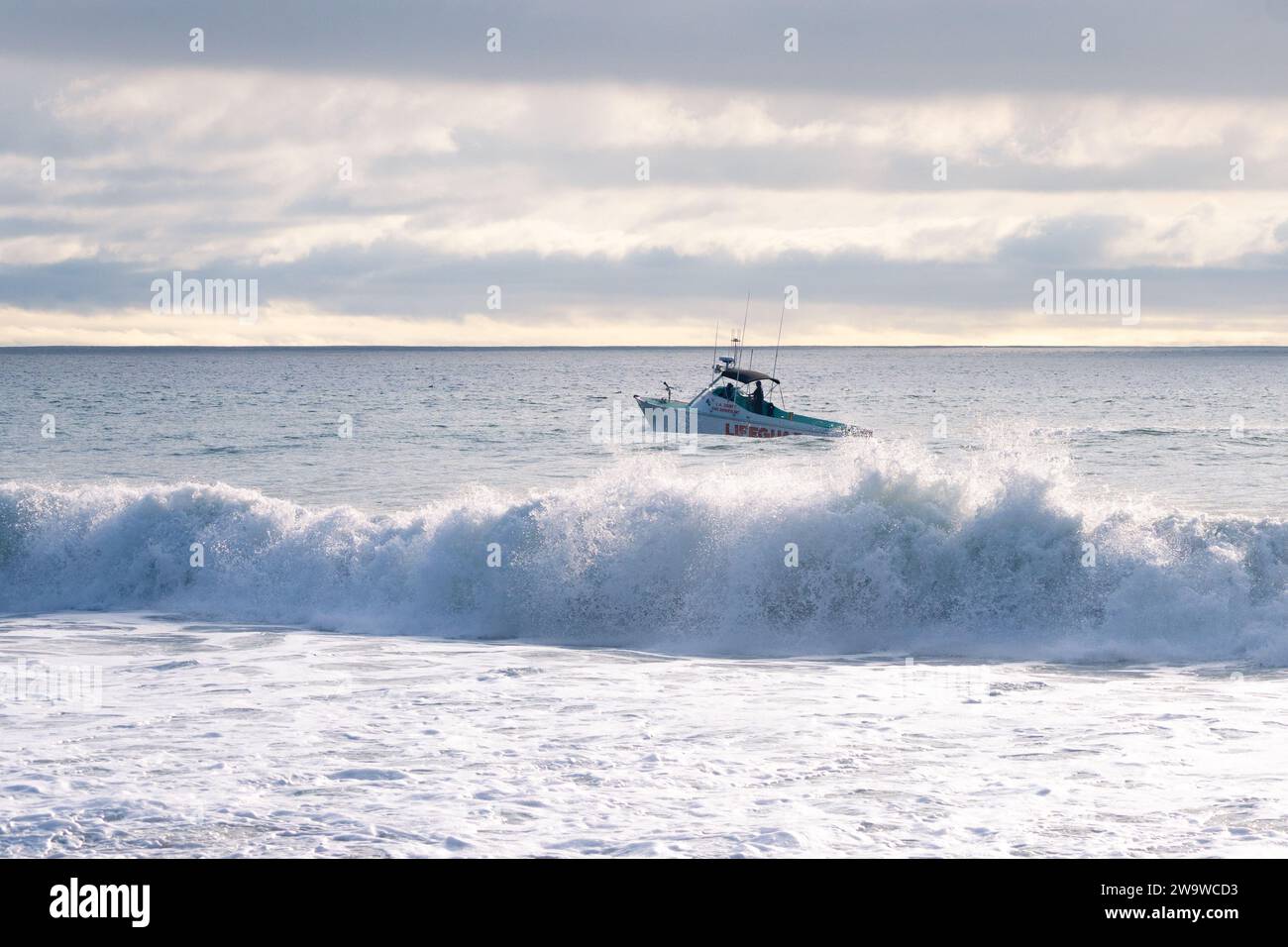 A lifeguard boat patrols the Southern California coastline during high surf conditions at Point Dume beach in Malibu, California USA Stock Photo