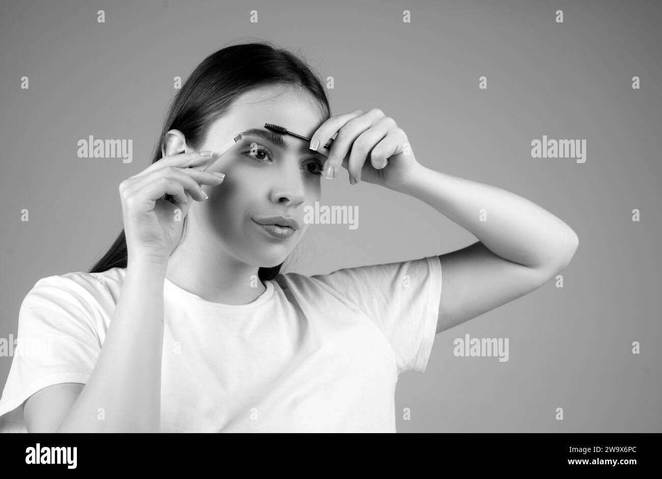 Combs eyebrows with a brush in a beauty salon. Woman with long eyelashes and thick eyebrows