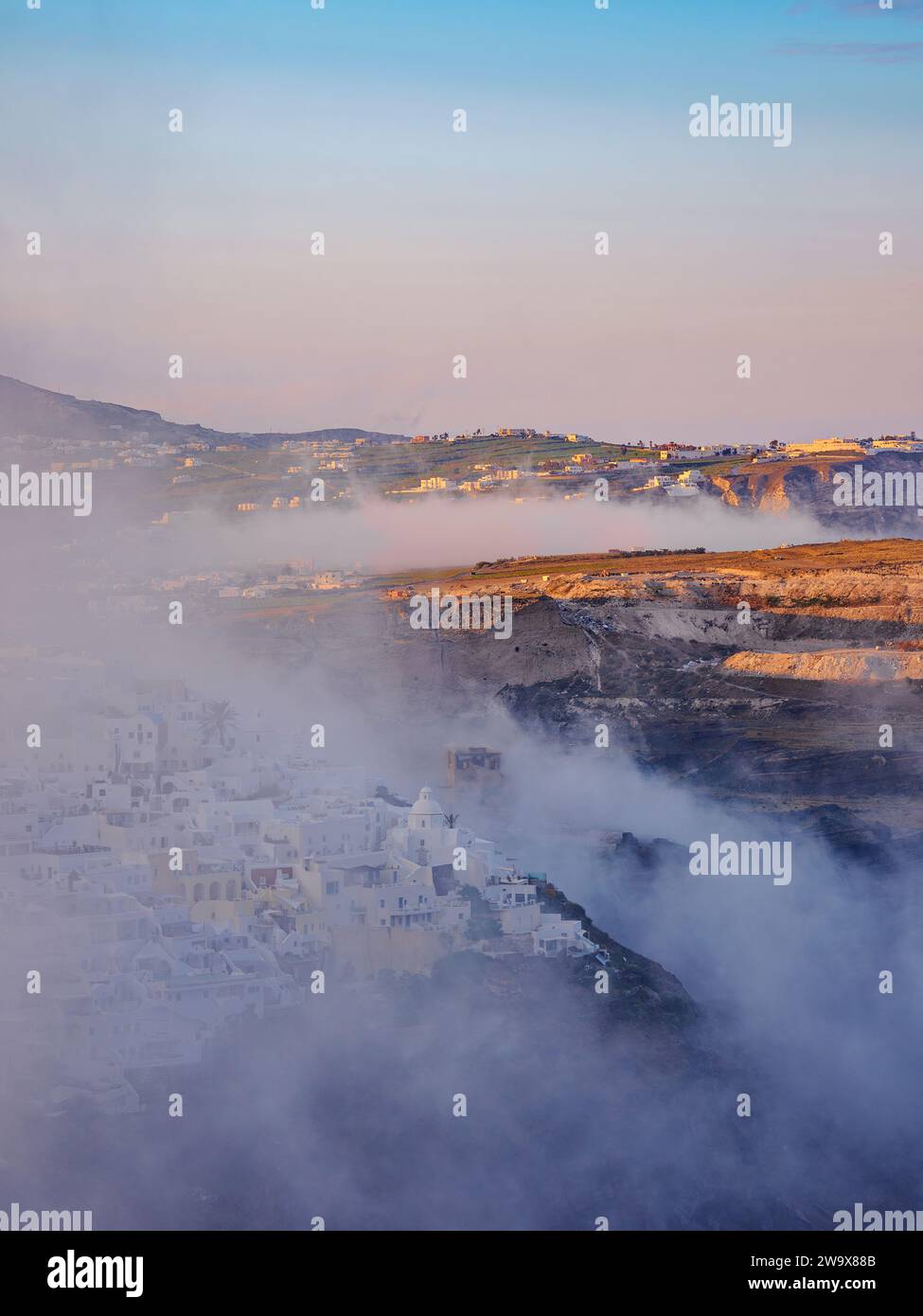 Cityscape of Fira at foggy sunrise, Santorini or Thira Island, Cyclades, Greece Stock Photo