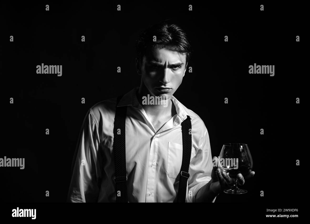 Elegant and stylish man in classical wear with wiskey. Stylish rich young man holding a glass of old whisky. Stock Photo