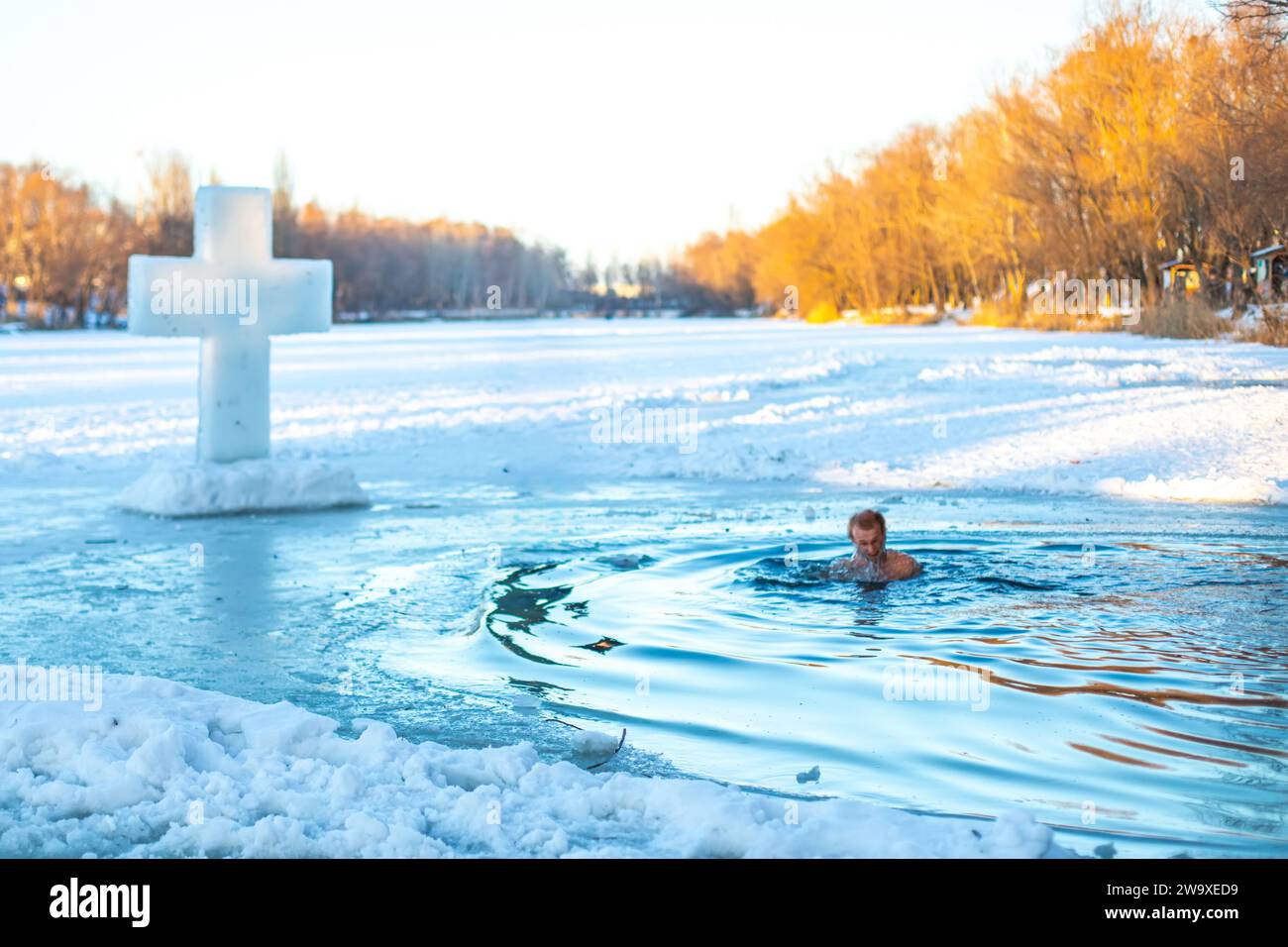 Feast of the Baptism of the Lord. The Orthodox rite of bathing in an ice-hole. Epiphany. A man bathes in ice water on a holiday. Dipping in water near Stock Photo