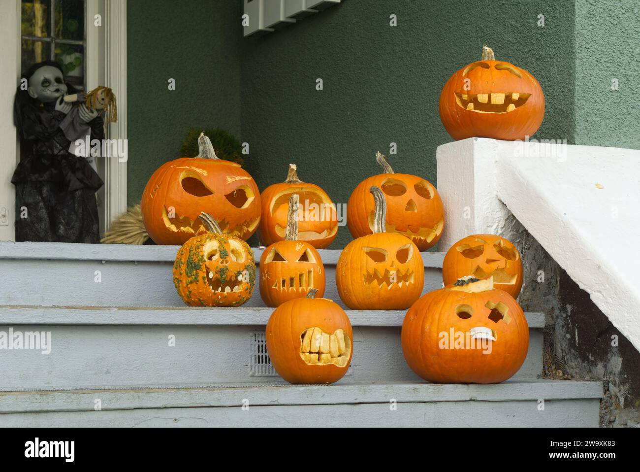 Humorous carved Halloween pumpkins displayed on the wooden front stairs of a house Stock Photo
