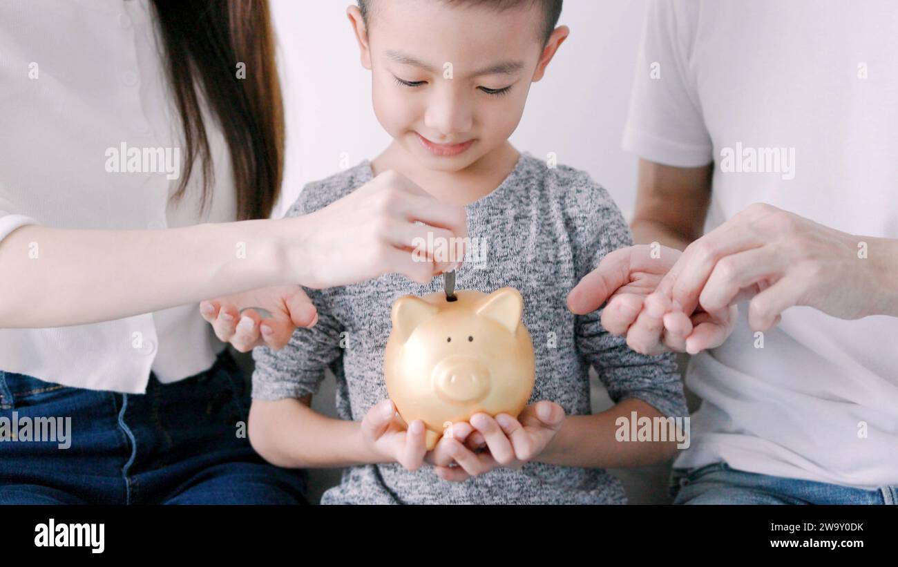 Happy family hands holding piggy bank. kid and parents put coins  into piggy bank Stock Photo