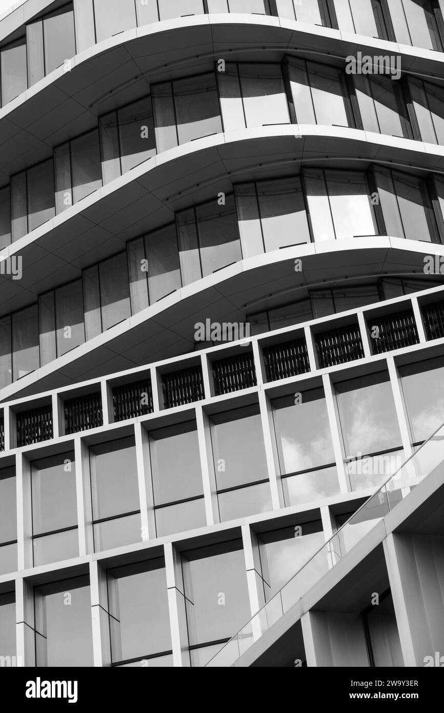 Monochrome architecture, curved lines of a modern building facade, pattern of windows and balconies, urban texture. Stock Photo