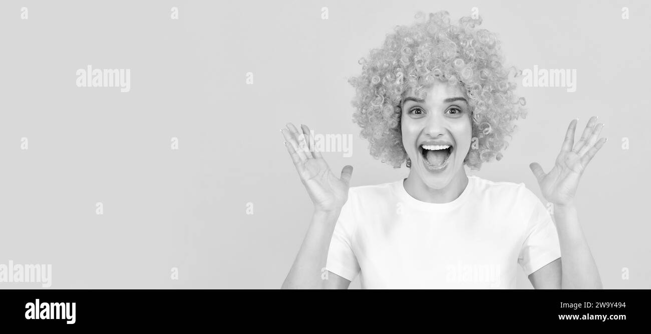 extremely happy funny girl with fancy look wearing orange hair wig on yellow background, happiness. Woman isolated face portrait, banner with copy Stock Photo