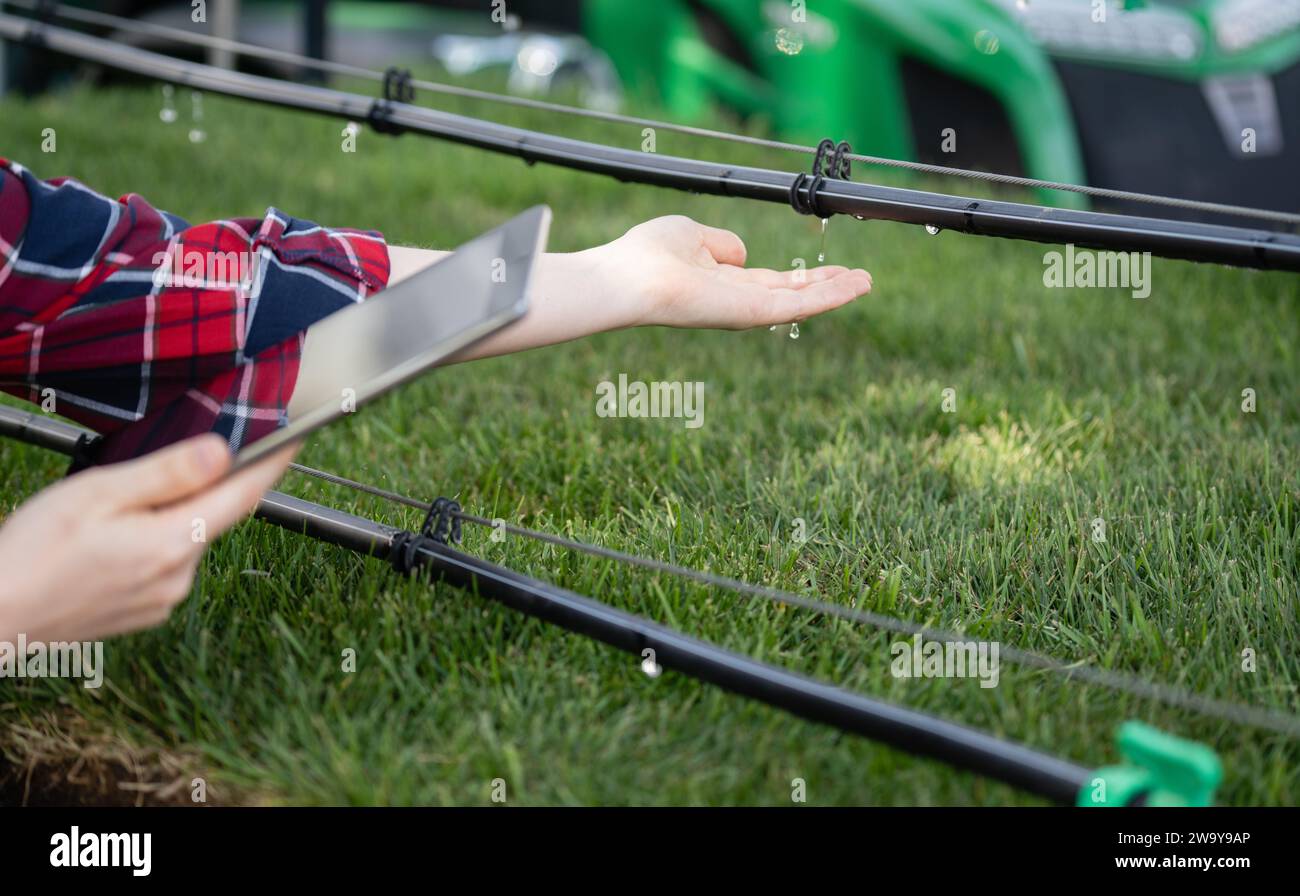 Farmer controls drip irrigation system with digital tablet. Stock Photo
