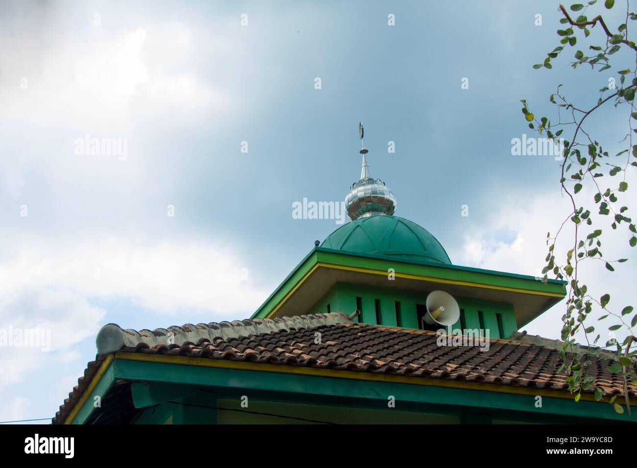 Traditional Indonesian mosque with setenlis dome and toa speakers against a cloudy sky background Stock Photo