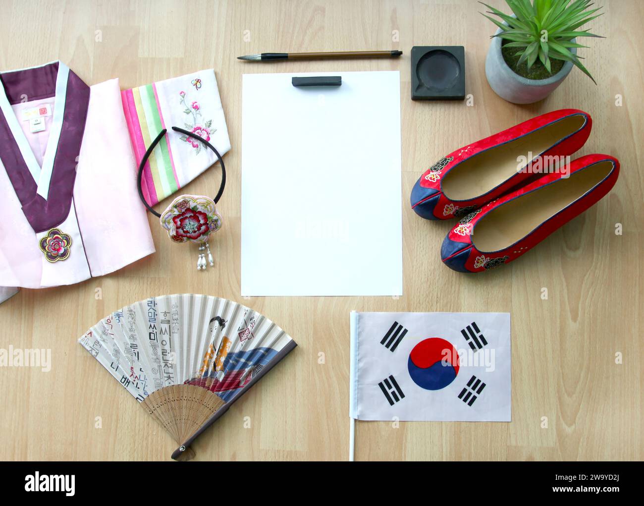 Korean gomusin shoes, a jeogori hanbok, buchae traditional fan and a hanbok hairband, the South Korean flag, blank paper, calligraphy brush and ink. Stock Photo