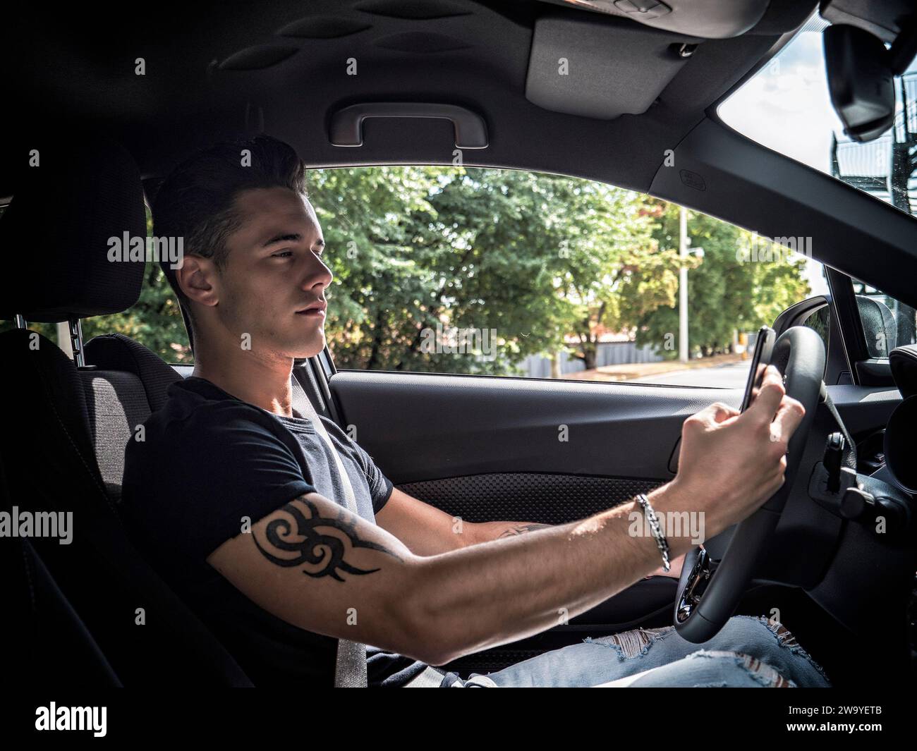 Handsome young man using mobile phone while driving a car Stock Photo