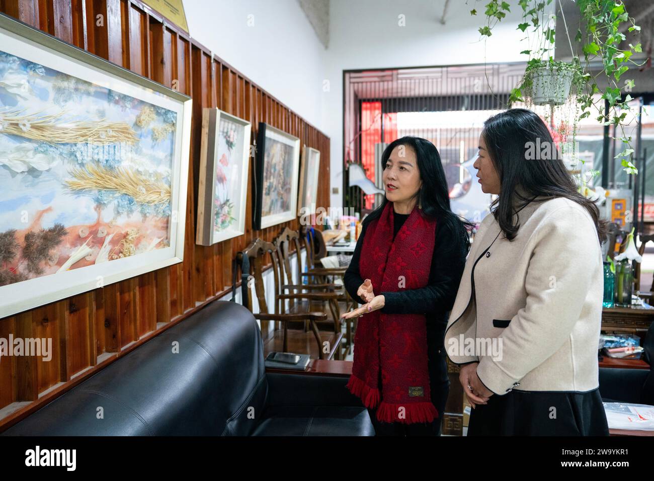 (231231) -- KUNMING, Dec. 31, 2023 (Xinhua) -- Yang Qiaoyan (L) introduces floral works at her workshop in Kunming City, southwest China's Yunnan Province, Dec. 26, 2023. About 30 years ago, the Dounan Flower Market was just a street with roadside stalls selling flowers, but today it has become Asia's largest fresh-cut flower trading market.During this winter at the market, vibrant flowers in various colors are auctioned and sold in an organized manner, attracting both tourists and flower merchants seeking purchases. Among the many florists here is Yang Qiaoyan, who has dedicated nearly a deca Stock Photo