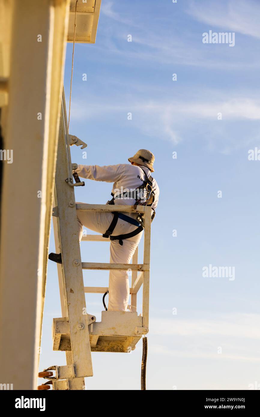 Workman working at height with safety equipment on board a ship. Tenerife, Canary Islands,Spain Stock Photo