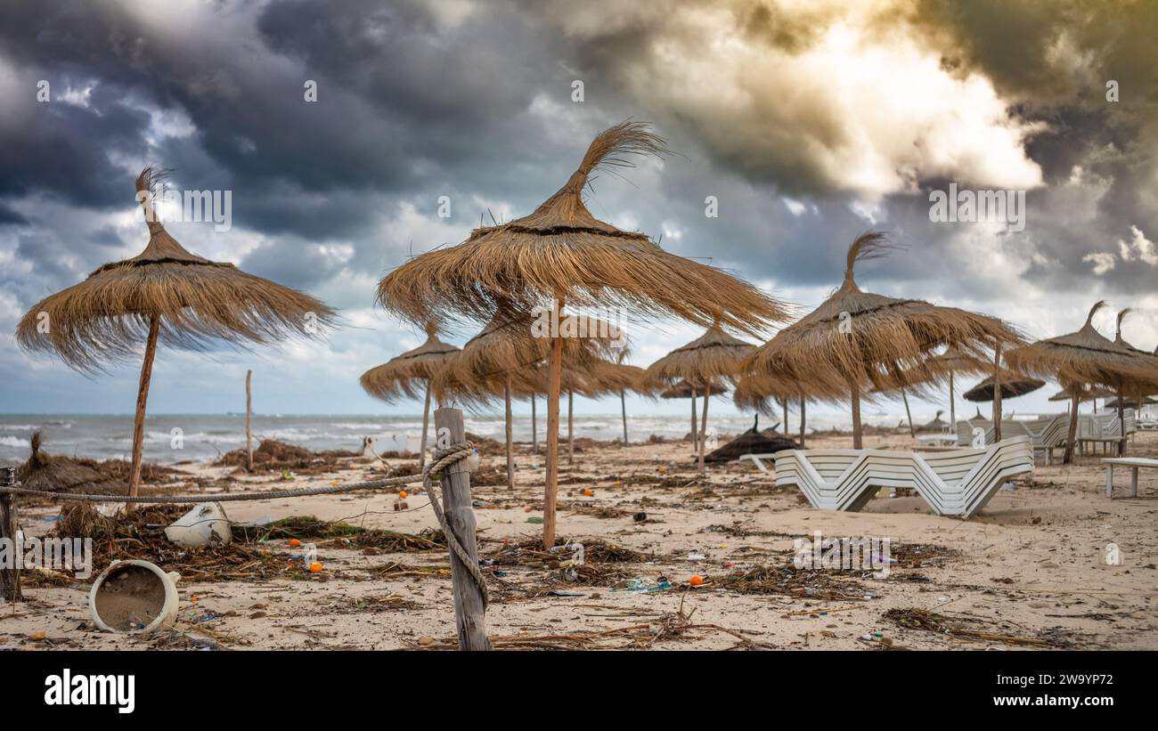 General rubbish and other detritus strewn under wind-blown parasols on Samara Beach in front of all-inclusive resorts in Sousse, Tunisia. Stock Photo