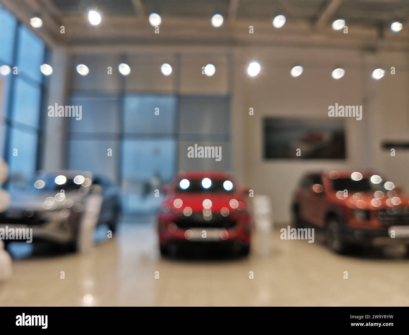 Blurred new car parked in modern showroom waiting for sales. Abstract background of blurred new cars dealership place. Stock Photo