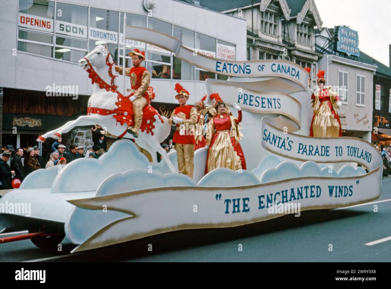 A parade float taking part in Eaton's Santa Claus Parade on Yonge Street, Toronto, Ontario, Canada, November 17, 1962. This float, ‘The Enchanted Winds’, promotes Eaton’s department stores with colourful costumes and a horse and rider up in the ‘clouds’. Attracting large crowds, the annual Toronto Santa Claus Parade (also known as The Original Santa Claus Parade) was first held in 1905 and is one of the largest in North America and the oldest Santa Claus parade in the world. It used to terminate at the downtown Eaton's store (later the Eaton Centre) at Yonge Street and Queen Street. Stock Photo