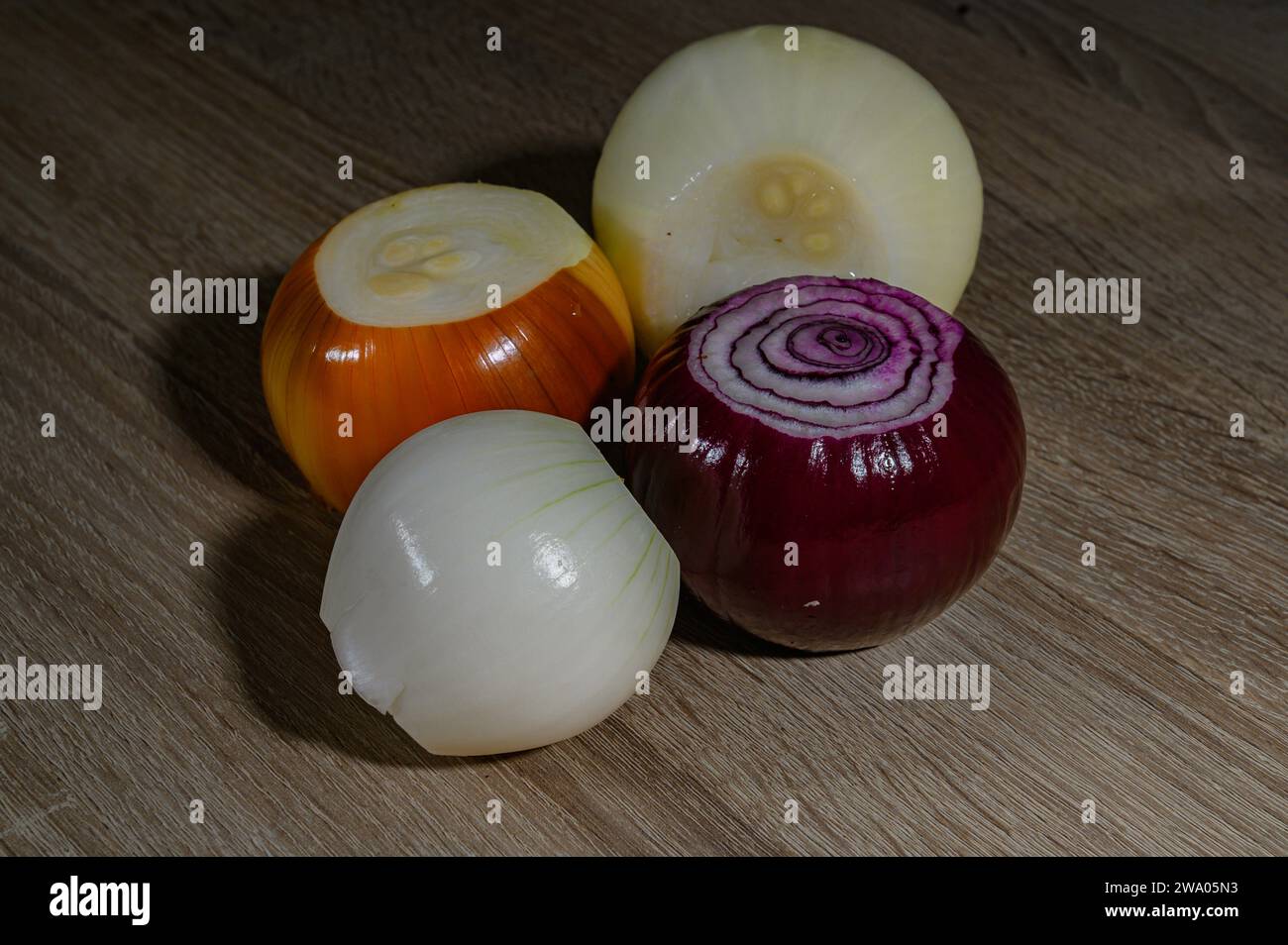 four onions, one of each type, a red or red onion, sweet white onion, normal onion and spring onion or French onion. on a wooden board Stock Photo