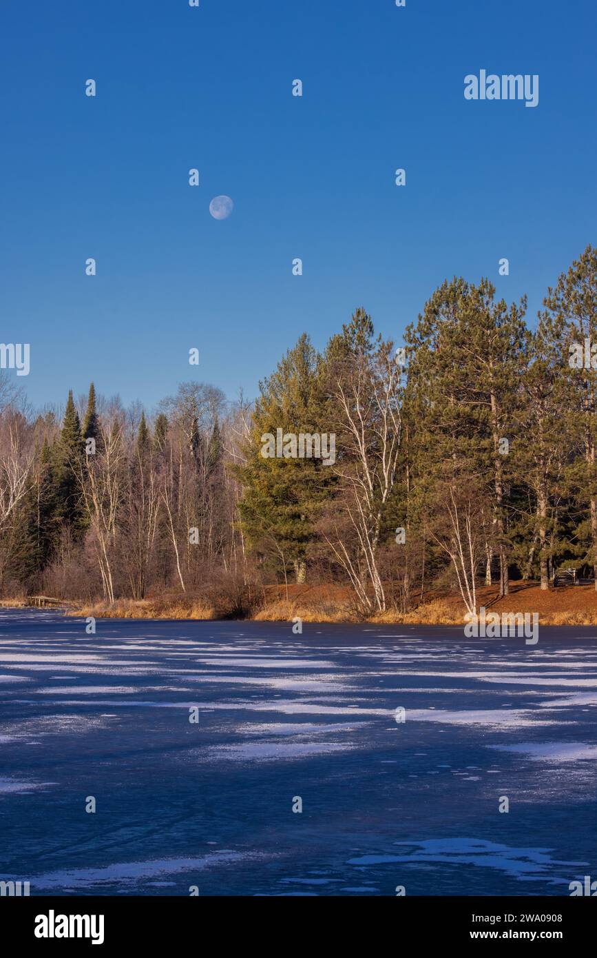 The moon setting over Loretta Lake in northern Wisconsin Stock Photo