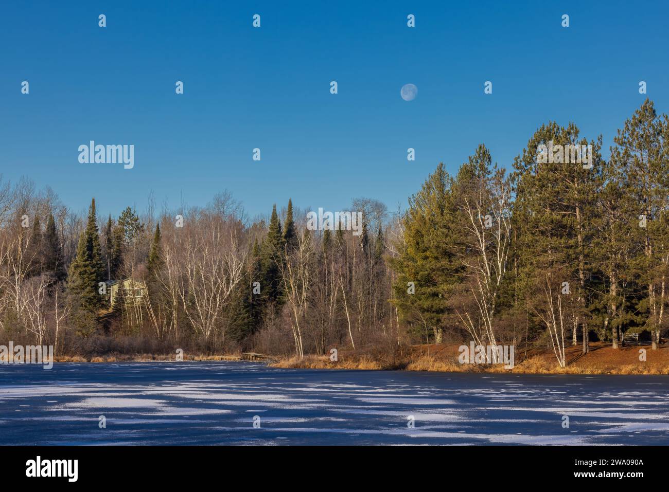 The moon setting over Loretta Lake in northern Wisconsin Stock Photo