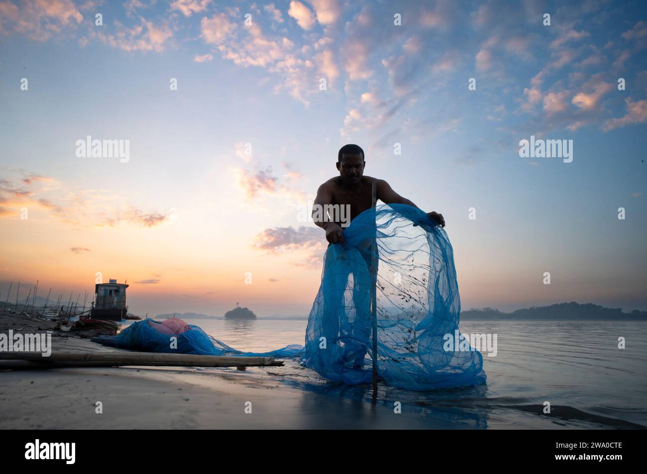 A fisherman prepare to lay his fishing net in the Brahmaputra river during sunset, in Guwahati