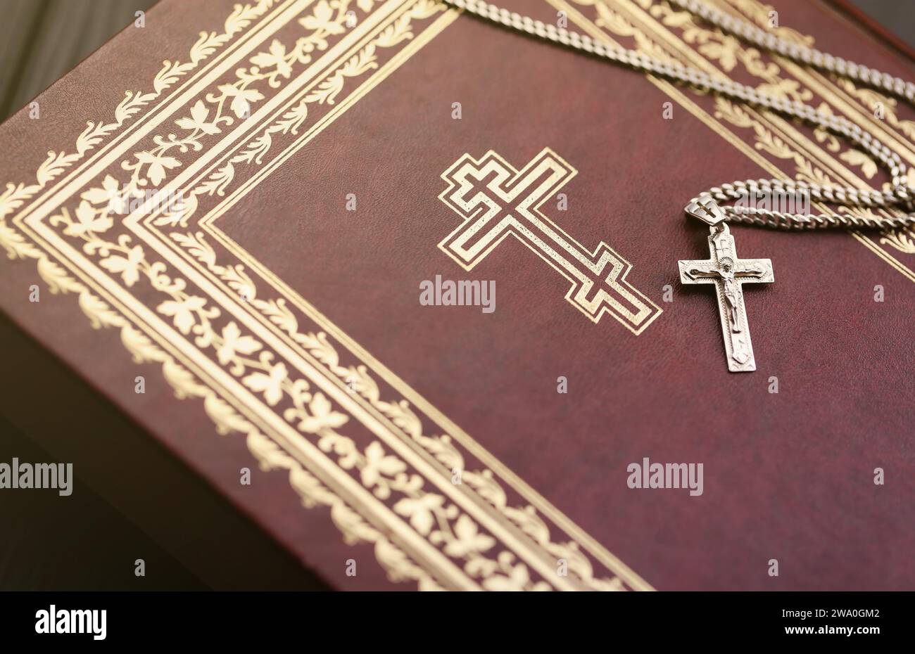 Silver necklace with crucifix cross on christian holy bible book on black wooden table. Asking blessings from God with the power of holiness, which brings luck and shows forgiveness. Stock Photo