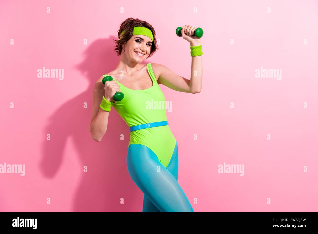 Photo portrait of lovely young lady lifting dumbbells training wear trendy green sport jumpsuit isolated on pink color background Stock Photo