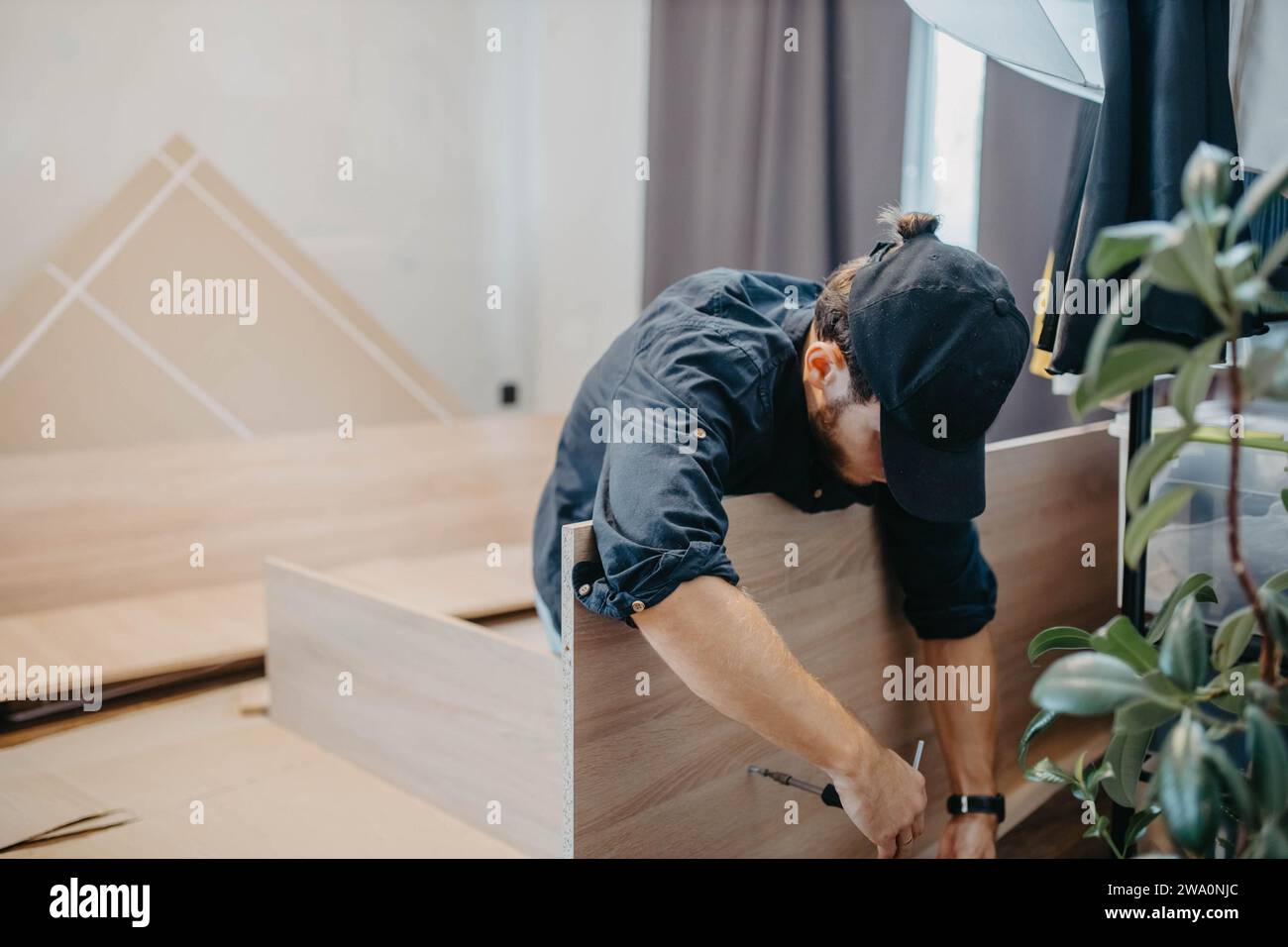 Young handsome carpenter assembling a wardrobe at a customer's home Stock Photo