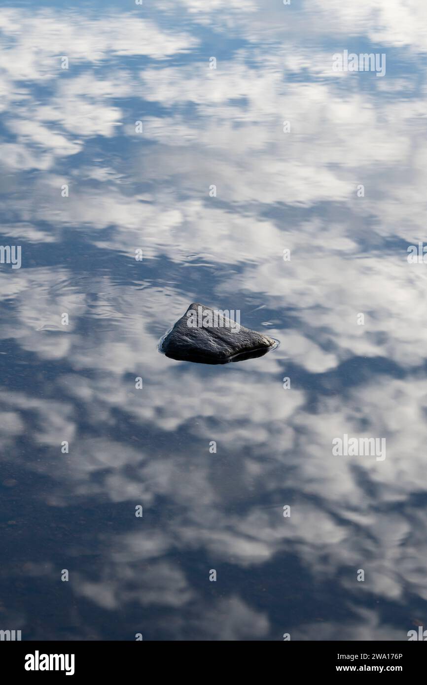 Clouds reflecting in a loch wih a rock breaking the surface. Loch Beinn a' Mheadhoin. Glen Affric, Highlands, Scotland Stock Photo