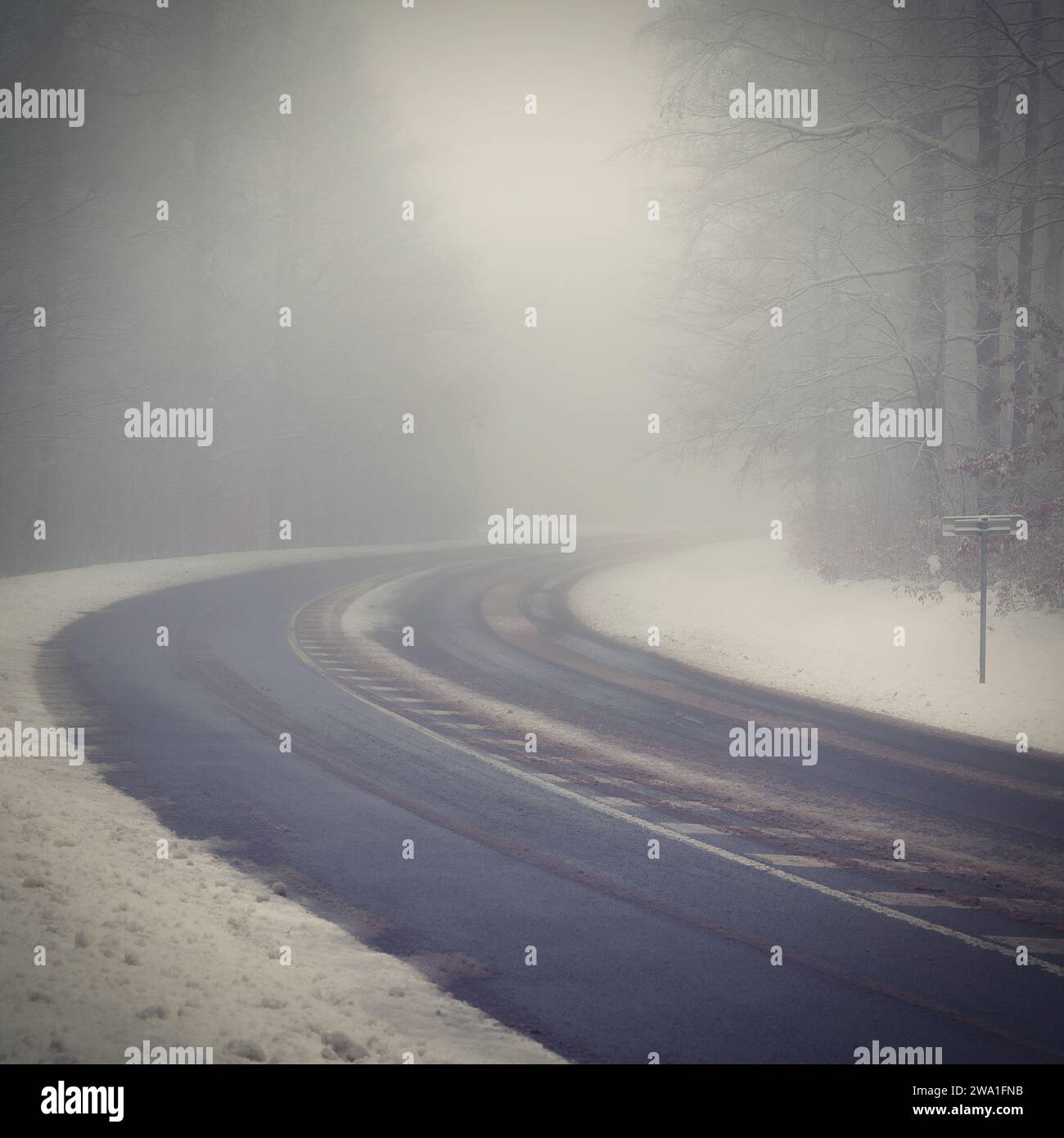 Bad weather driving - foggy hazy country road. Motorway - road traffic. Winter time. Autumn - fall.  Snow and frost on the road in winter. Stock Photo