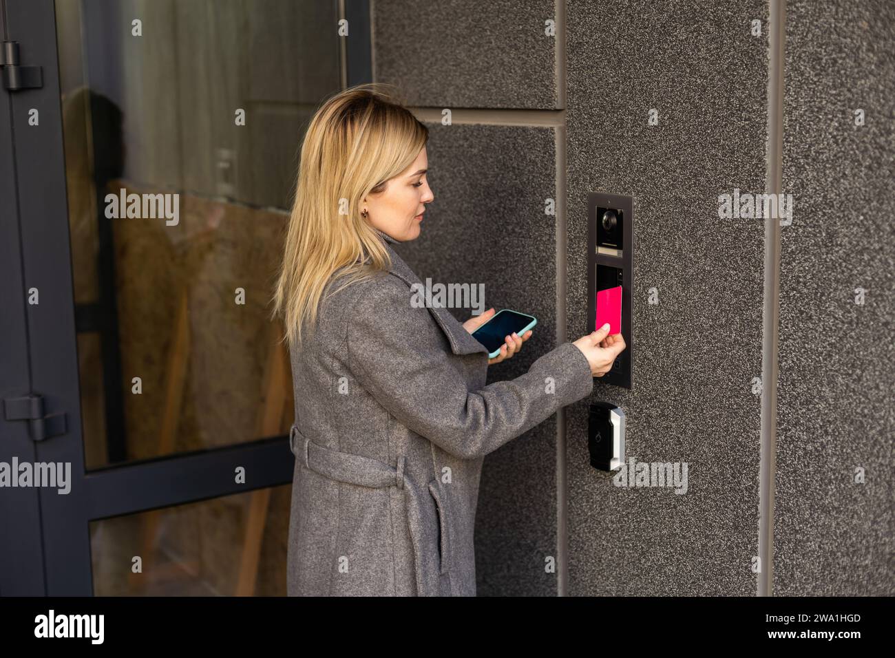 Middle aged woman pushing button of intercom Stock Photo