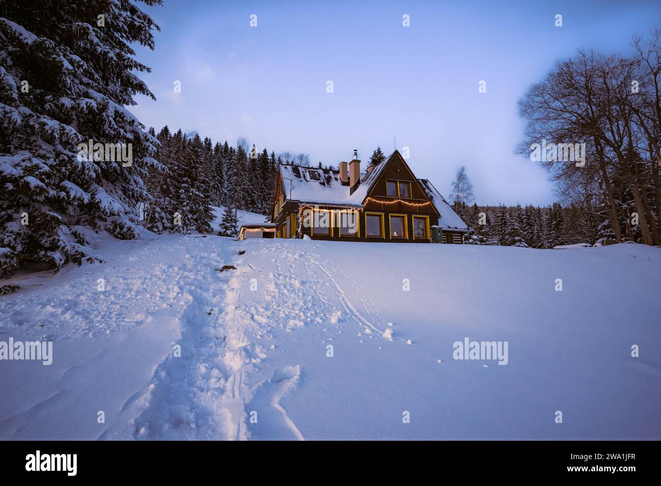 Magic winter cabin covered with white snow and decorated with Christmas lights. Fantasy atmosphere on Bohemia mountains. Stock Photo