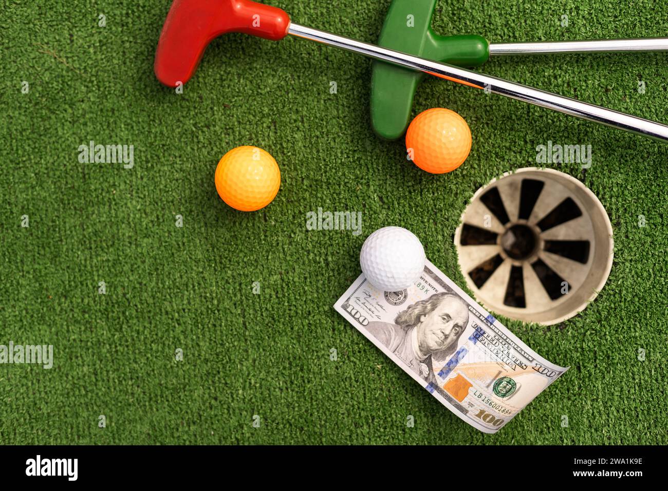 Mini Golf club, ball and money on the artificial grass Stock Photo