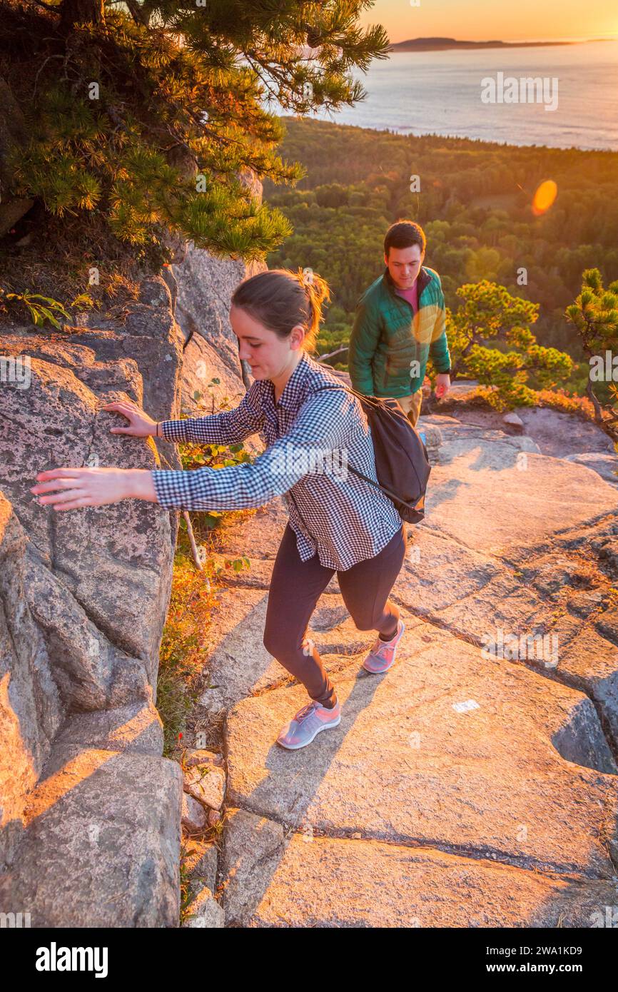 Young couple climbing on Beehive in fall in Acadia National Park, Maine, USA Stock Photo