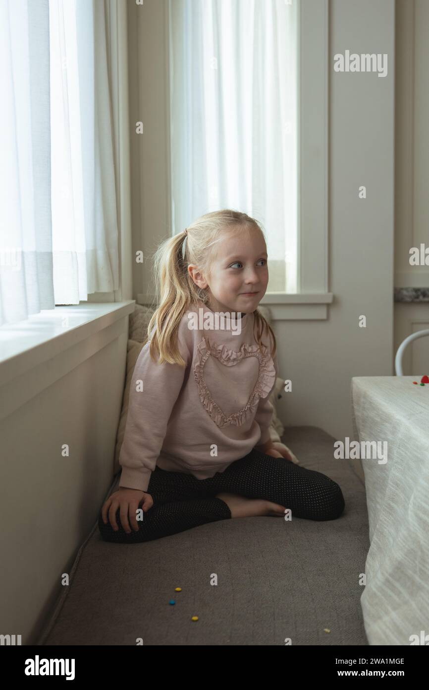Young girl cheekily giggles while in family kitchen Stock Photo