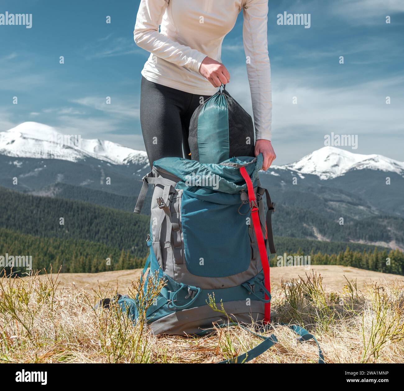 Young Woman Traveller Puts Out a Duffel Bag from Her Backpack Stock Photo