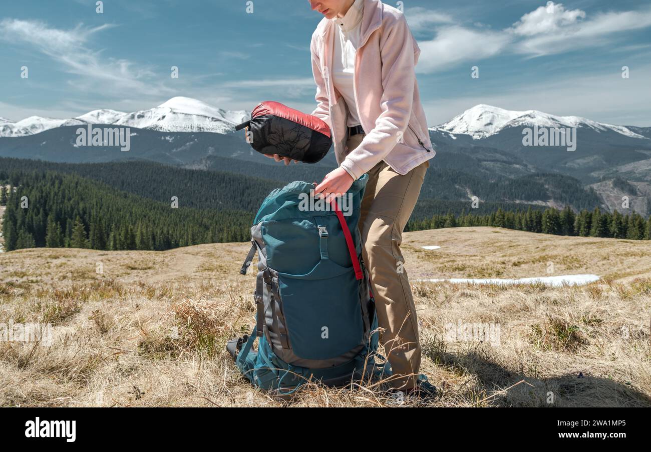 Young Woman Traveller Puts Out a Duffel Bag from Her Backpack Stock Photo