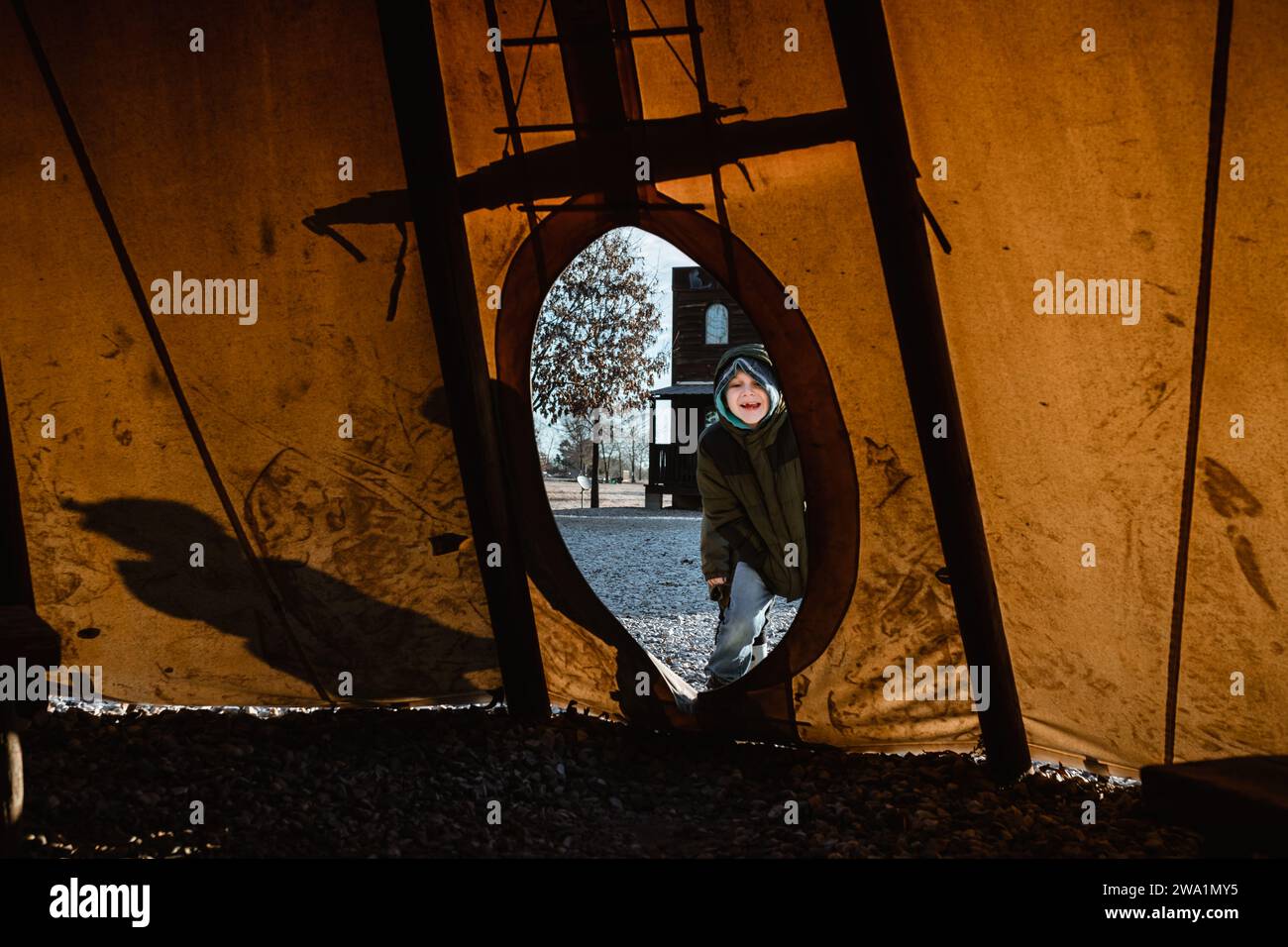 Happy child looking into teepee entrance during winter day Stock Photo