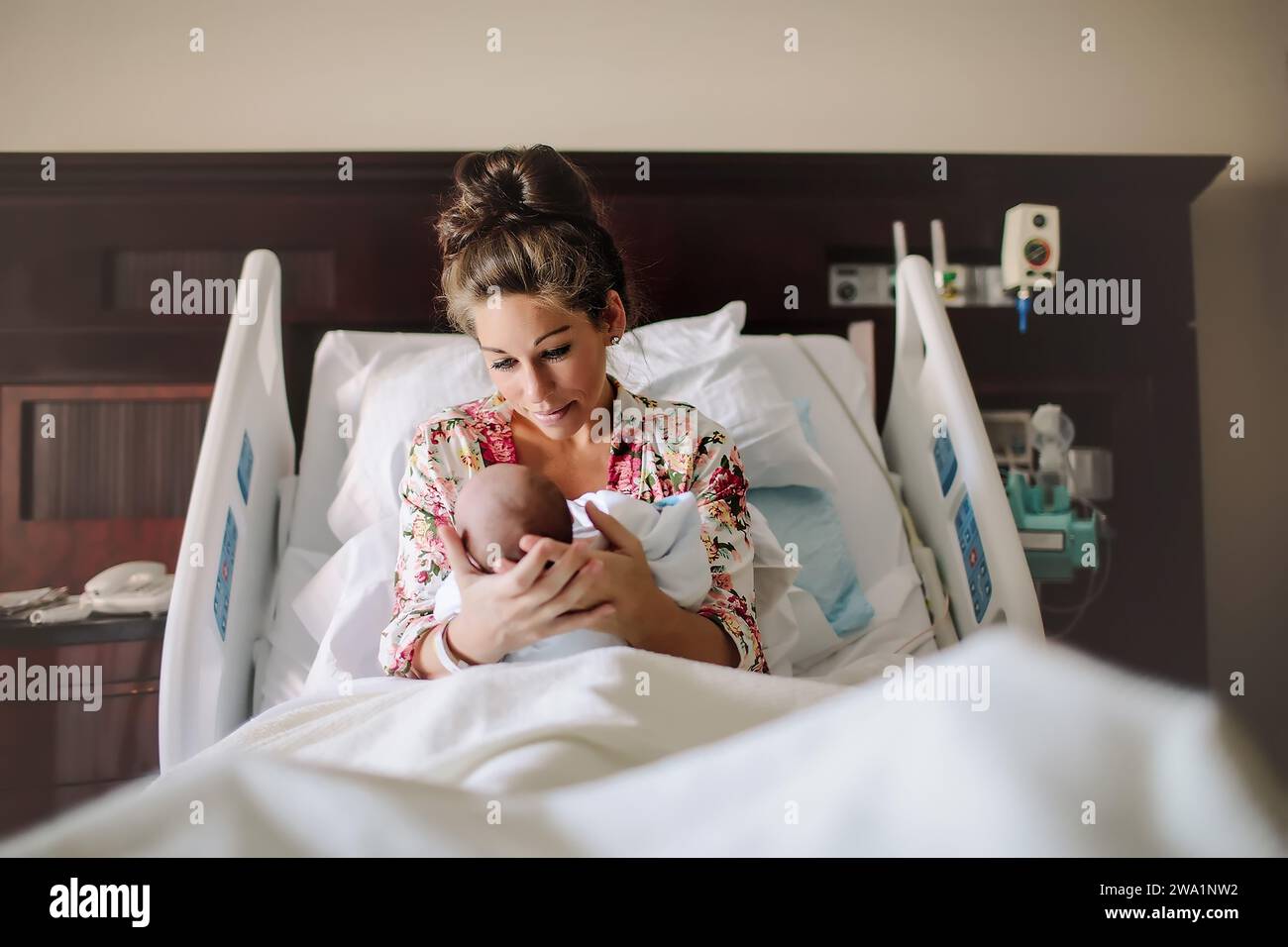 Young mother looking at her newborn baby while in a hospital bed Stock Photo