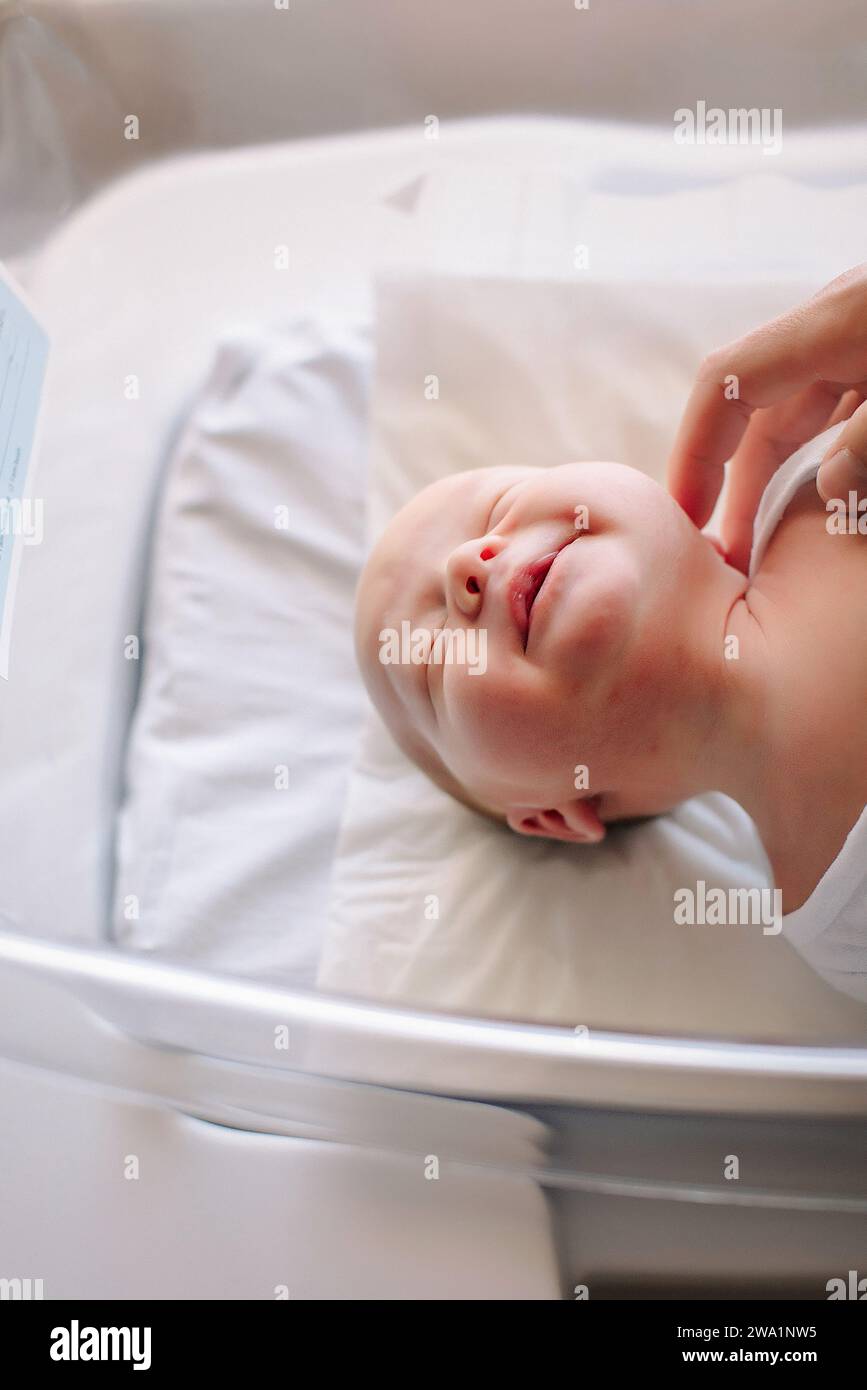 newborn baby stretching in hospital basinet Stock Photo