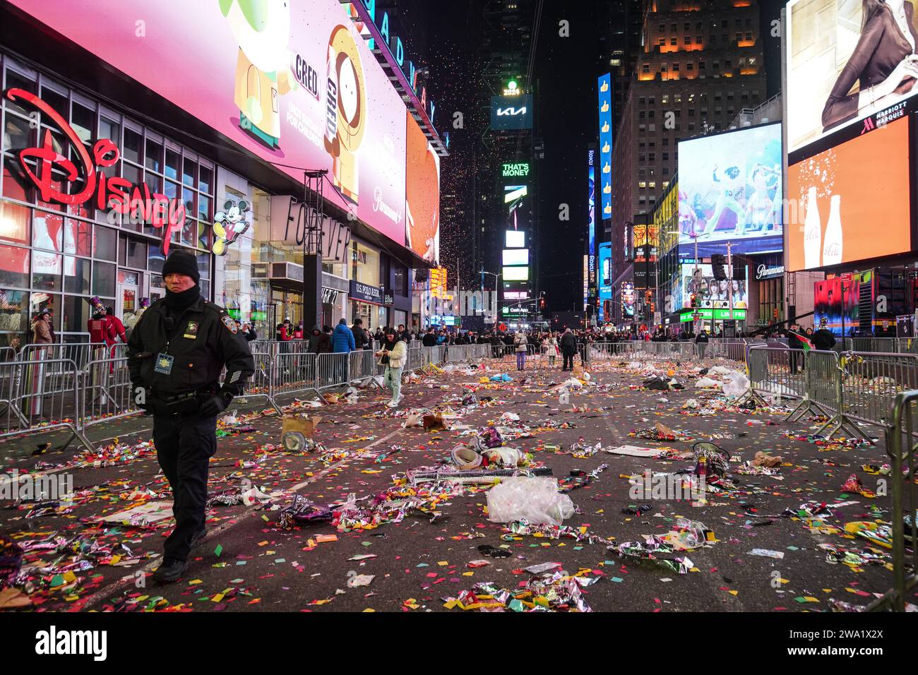 A police officer walks at Times Square when the confetti and discarded debris on the ground. Following the traditional countdown celebration and iconic ball drop at Times Square, the aftermath reveals a scene strewn with remnants of confetti and discarded debris. Swiftly after the revelry, the City of New York's Department of Sanitation (DSNY) mobilizes a dedicated team of cleanup workers to swiftly tackle the mammoth task of restoring Times Square to its pristine state. (Photo by Michael Ho Wai Lee/SOPA Images/Sipa USA) Stock Photo