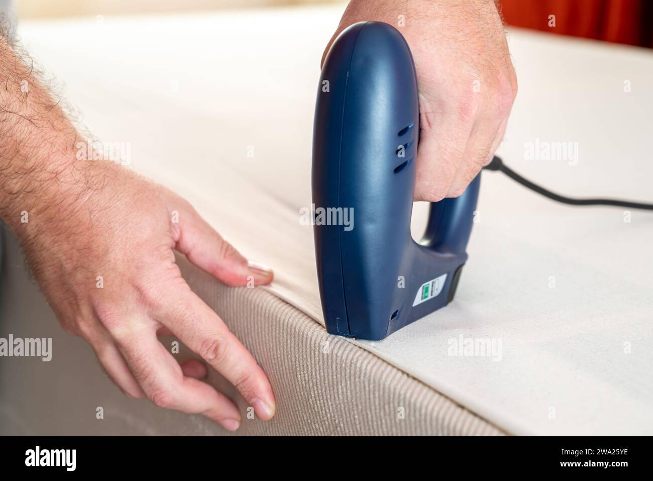Worker stapling sofa lining with electric staple gun Stock Photo