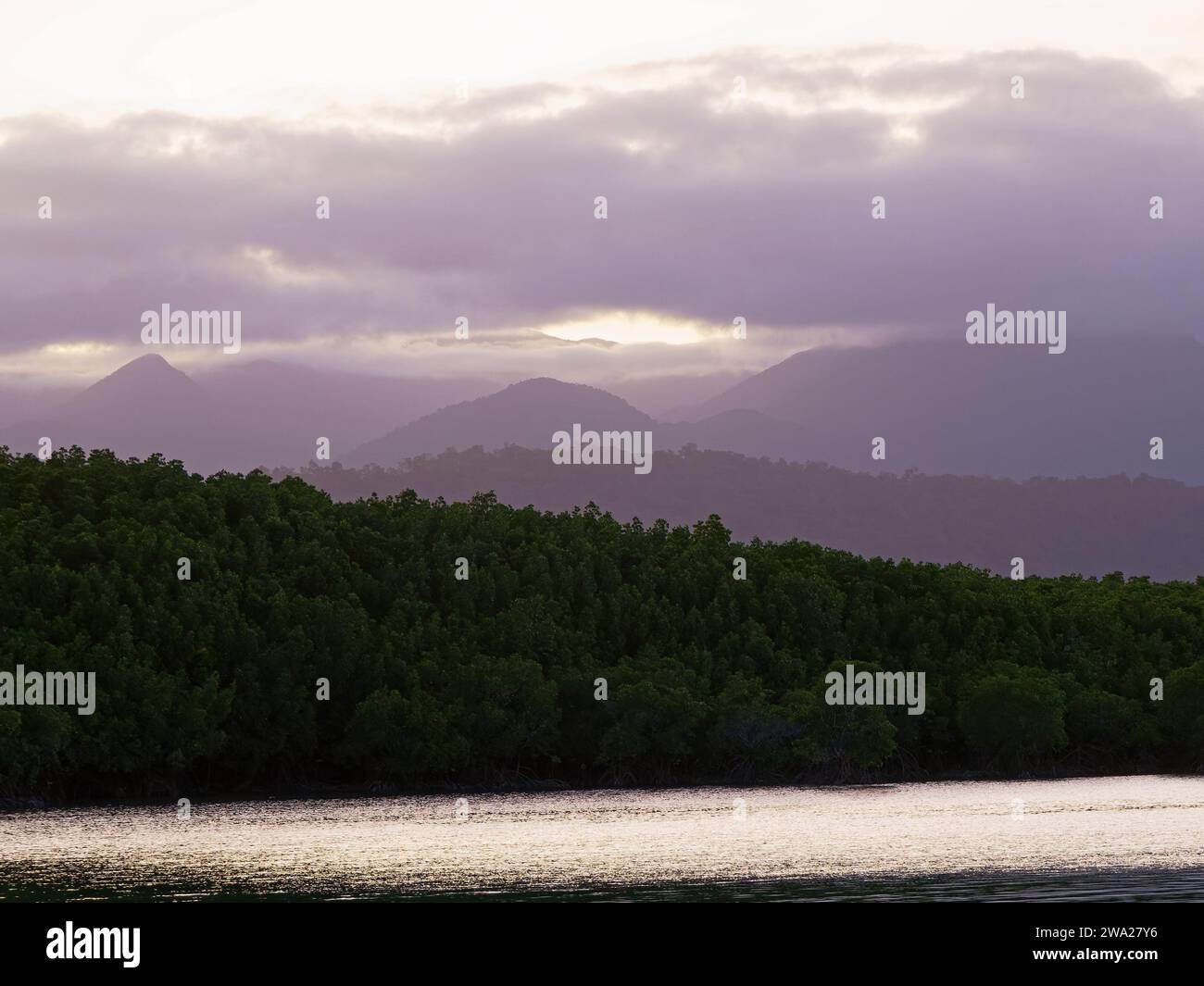 View of the sun setting over the distant hills in Port Douglas Queensland Australia Stock Photo