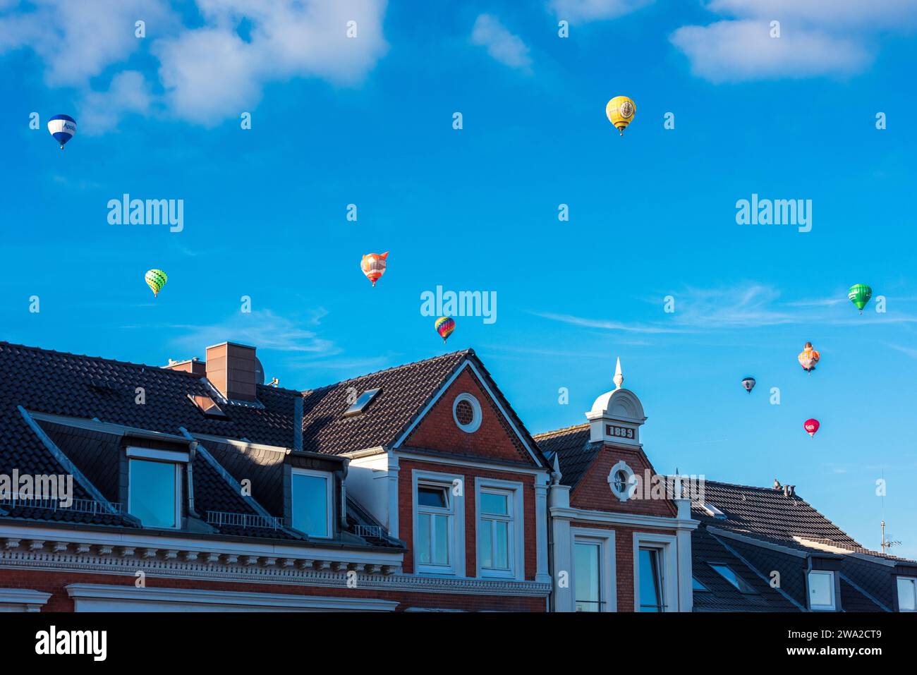 Bunte Heißluftballons über den Dächern der Kieler Altstadt vor blauem Himmel im Sommer *** Colorful hot air balloons over the rooftops of Kiels old town against a blue sky in summer Stock Photo