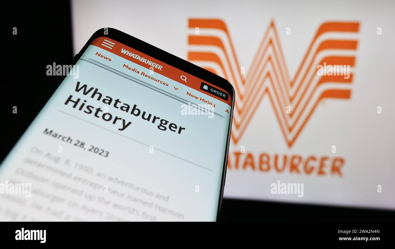 Mobile phone with website of US fast food company Whataburger Restaurants LLC in front of business logo. Focus on top-left of phone display. Stock Photo