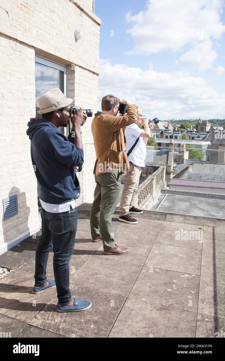 Photographers in a line photographing the city of Oxford from the roof of Weston library in the ...