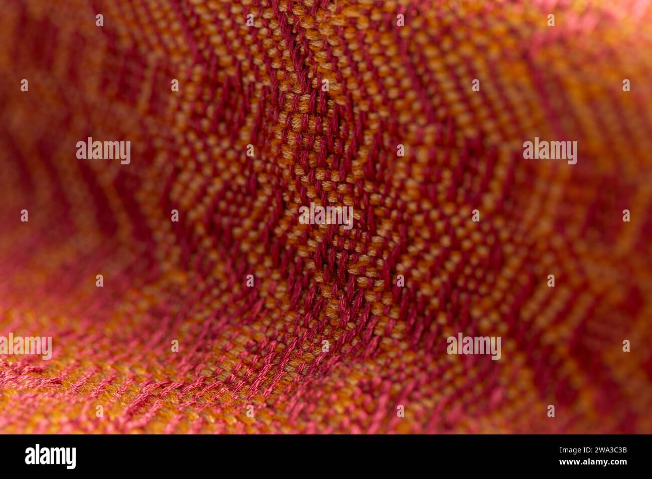 woven fabric of varied twill weaves in bright red and orange colors, detailed close up macro shot with a shallow depth of field Stock Photo