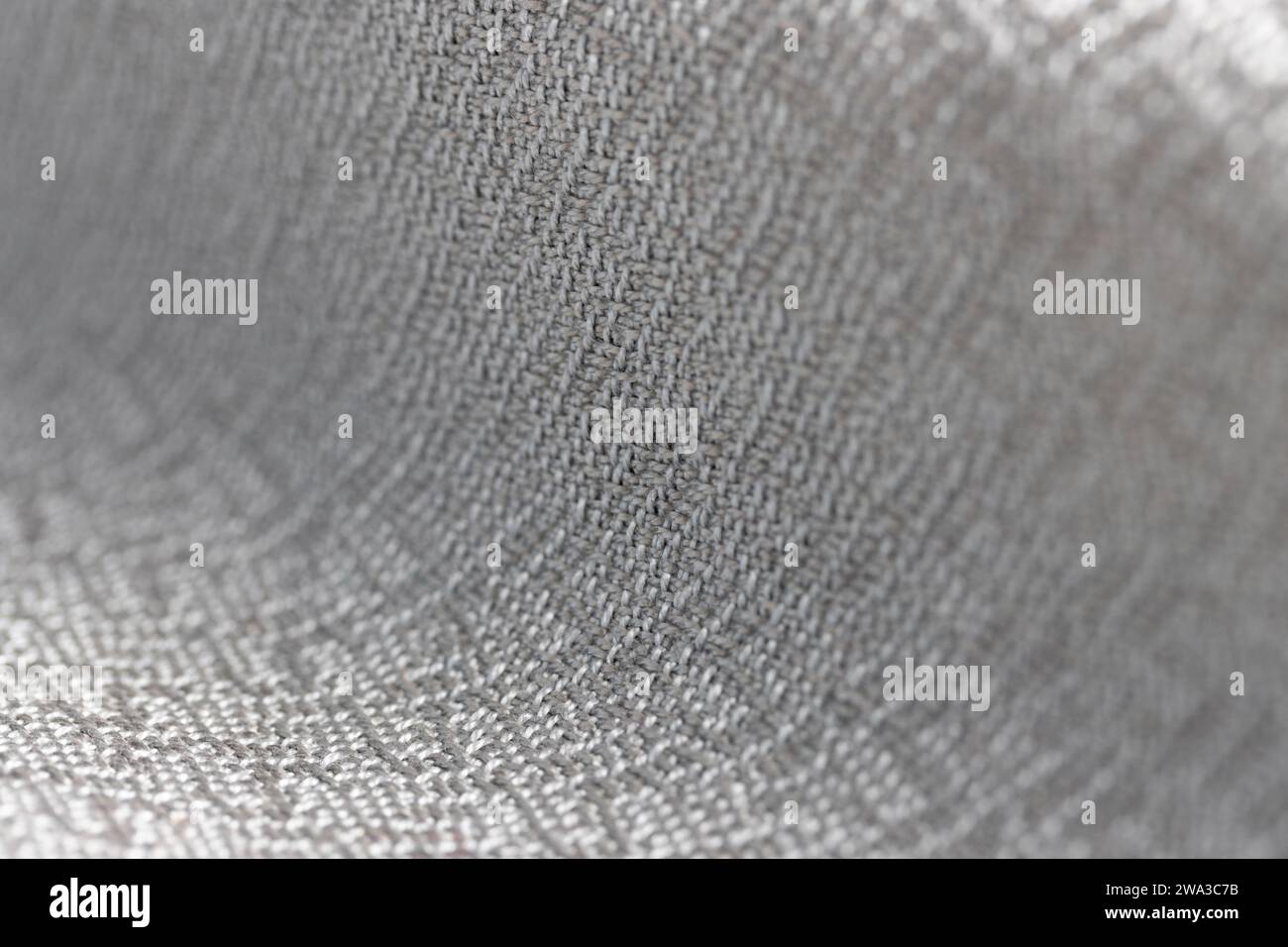 draped gray shiny crepe weave fabric, close up macro with very shallow depth of field, shows weave and fiber detail, neutral color background Stock Photo