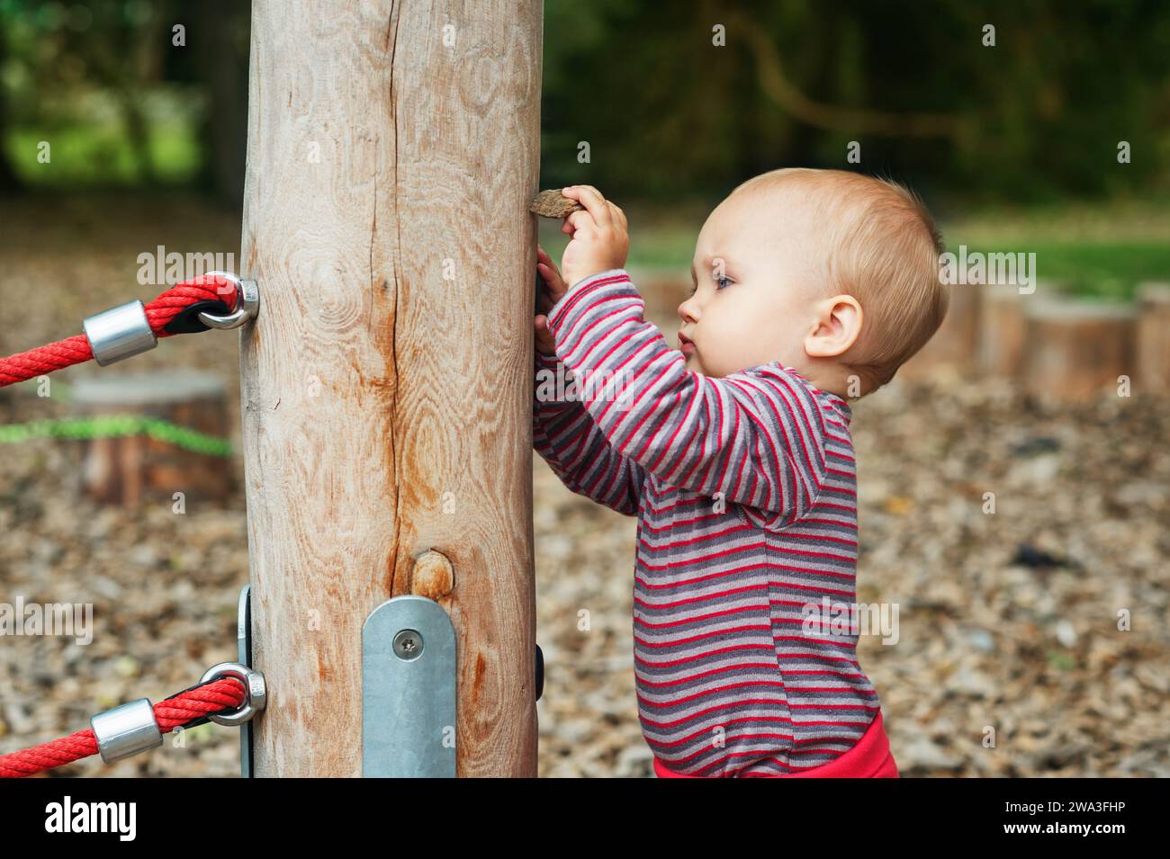 Outdoor portrait of adorable baby girl having fun on playground, cute little 9-12 months child playing outdoors Stock Photo