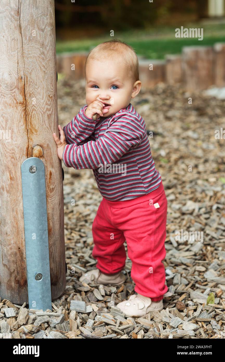 Outdoor portrait of adorable baby girl having fun on playground, cute little 9-12 months child playing outdoors Stock Photo